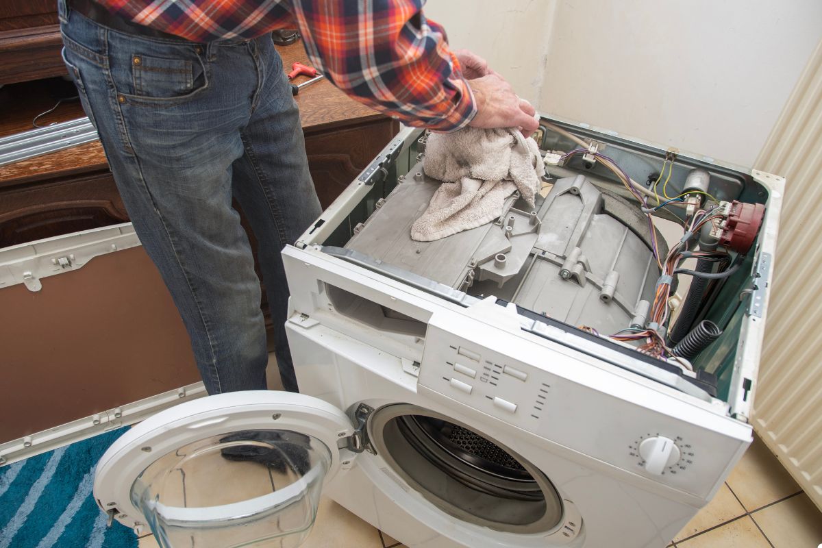 A man stands beside a washing machine, ready to do laundry in a bright, clean laundry room.