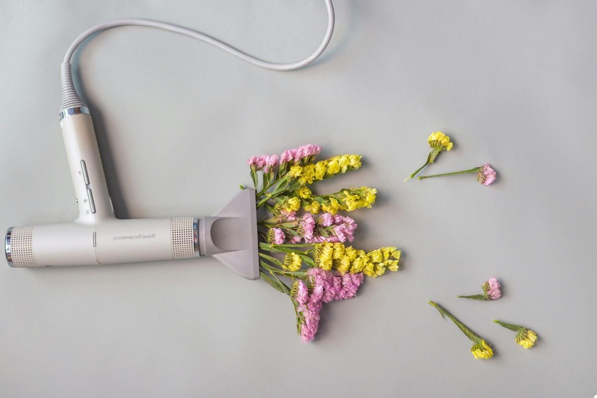 A hair dryer surrounded by colorful flowers and a decorative flower pot, showcasing a blend of beauty and functionality.